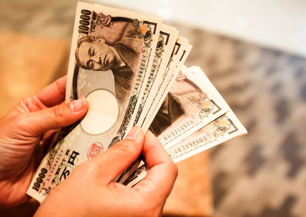 persona che agita una grossa somma di banconote giapponesi in yen.
