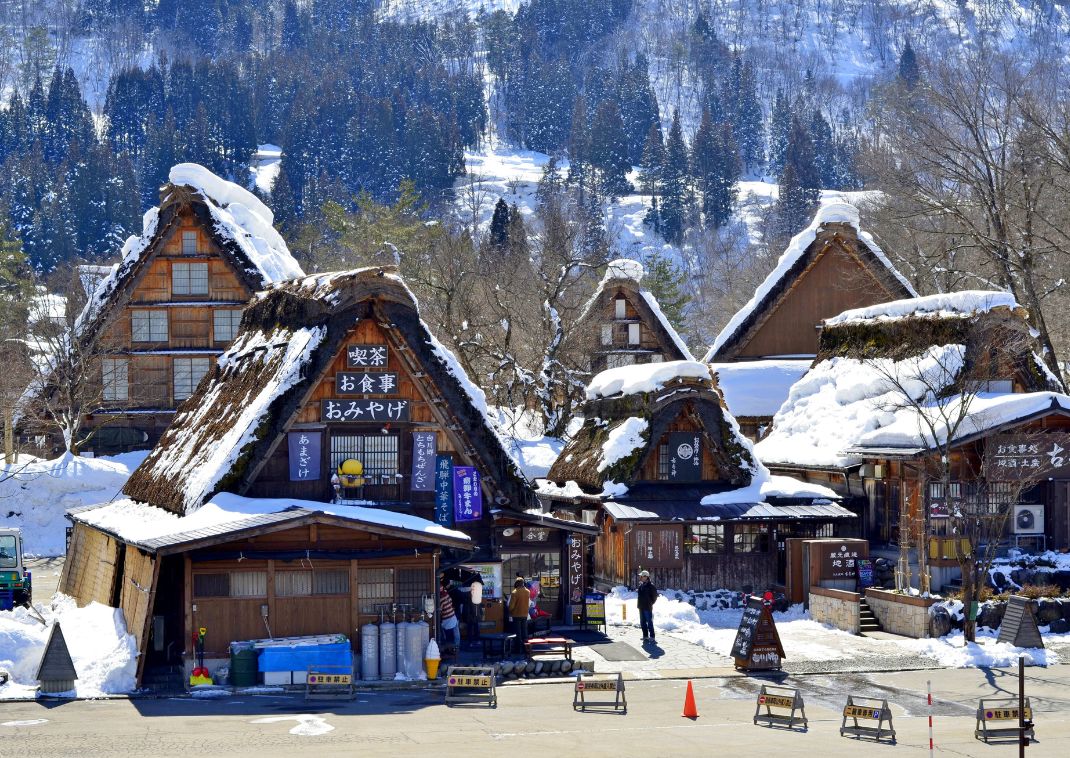 Tradizionali case coloniche Gassho-zukuri di Gokayama ricoperte di neve, con ripidi tetti in paglia progettati per gli inverni rigidi, circondate da montagne e pini.