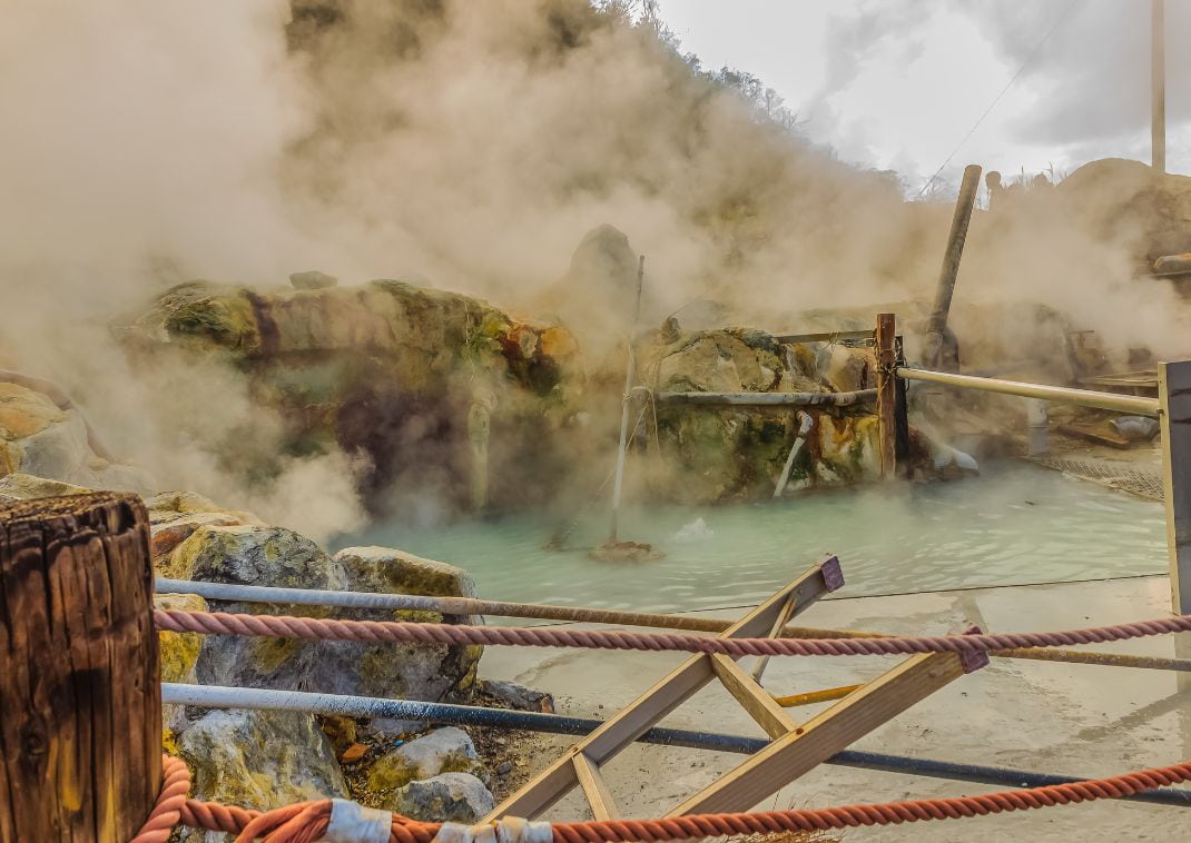 Stagno termale di Owakudani con nebbia e fumarole sulfuree attive