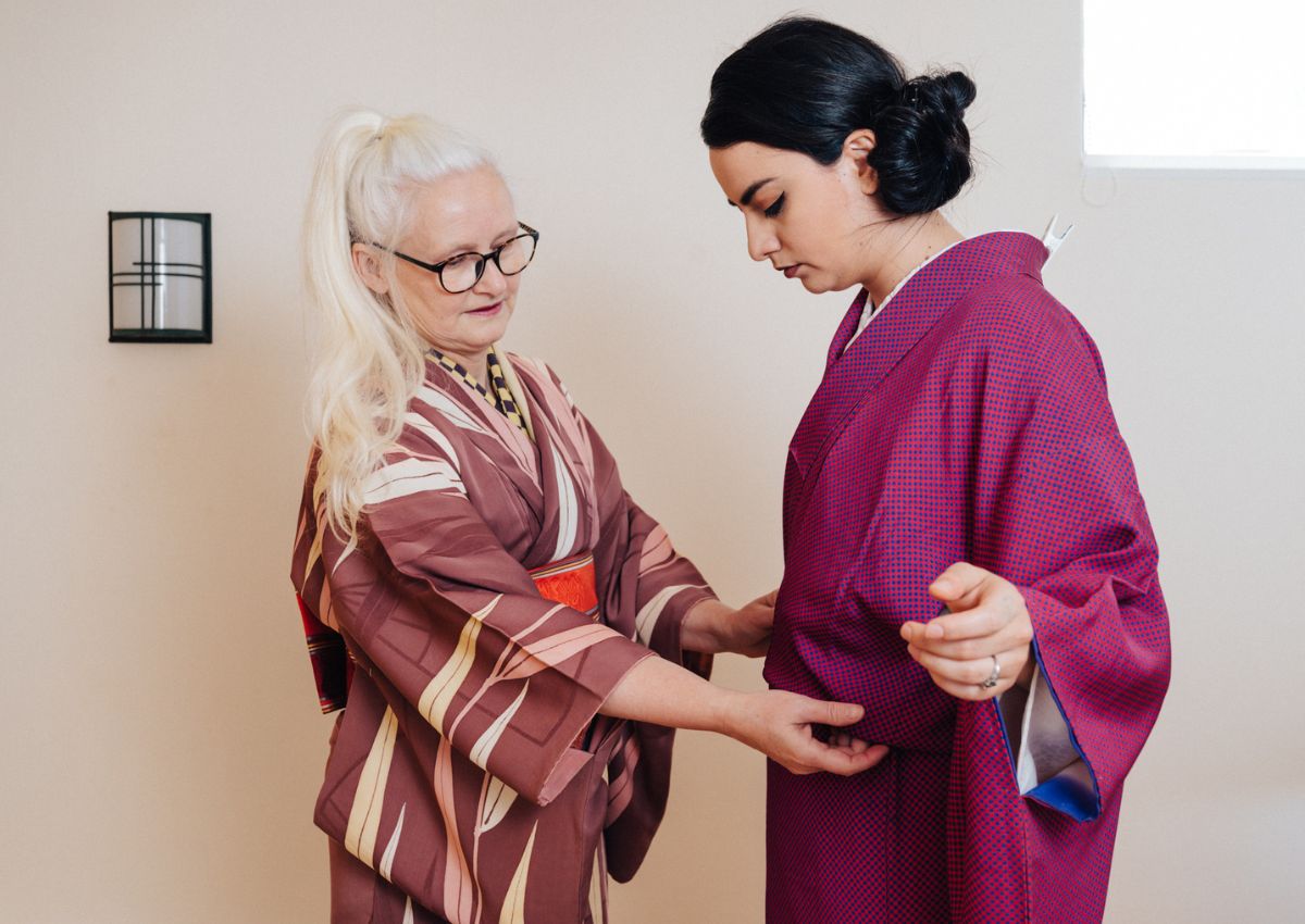 Istruttrice di kimono che aiuta una donna durante la vestizione