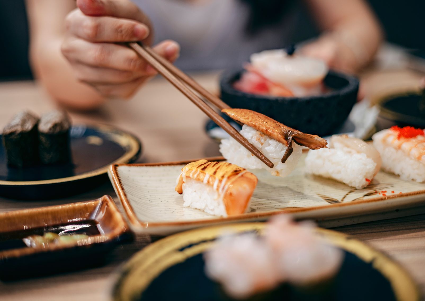 una persona usa le tradizionali bacchette giapponesi per mangiare il sushi