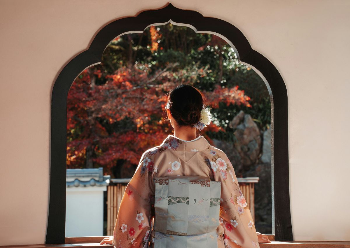 Donna in kimono ammira il foliage osservando attraverso una finestra, Giappone