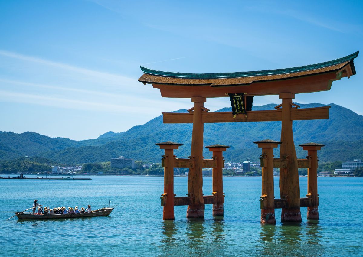 Visitatori in barca davanti al torii galleggiante di Miyajima, Giappone
