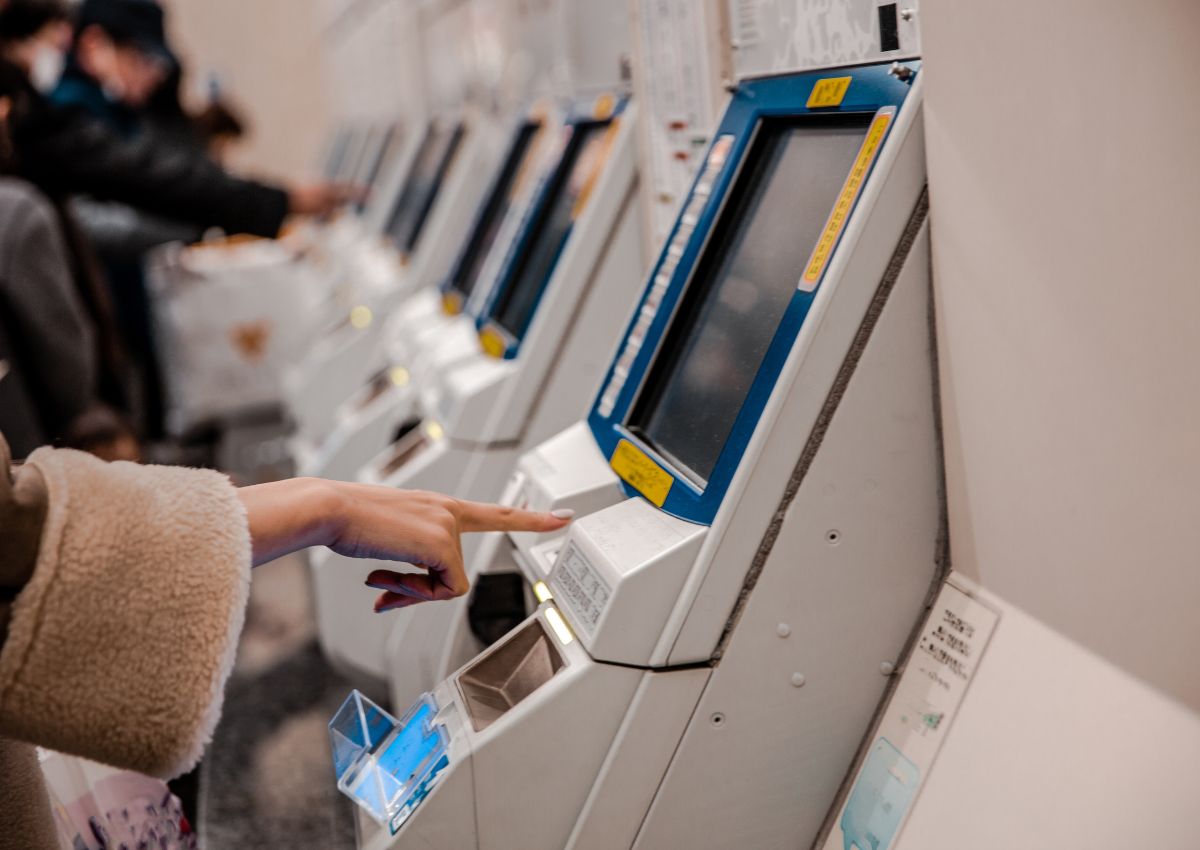 Donna che acquista i biglietti da un distributore automatico, Giappone