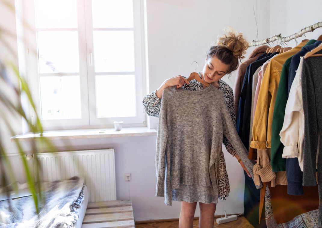 Donna che sceglie cosa indossare a casa prima di preparare la valigia