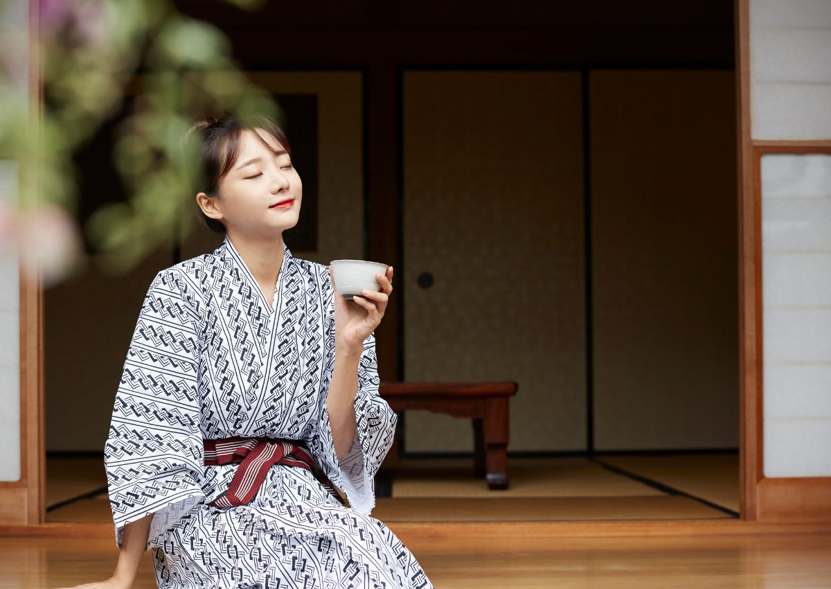 donna vestita con yukata sorseggia un tè in una camera di ryokan tradizionale
