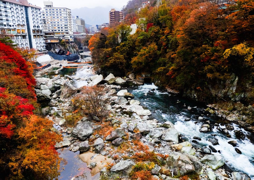 Foliage autunnale lungo un fiume giapponese con alberi colorati