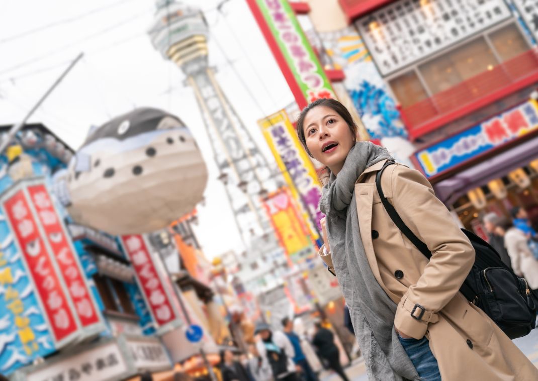 Giovane donna asiatica che esplora la zona Shinsekai di Osaka