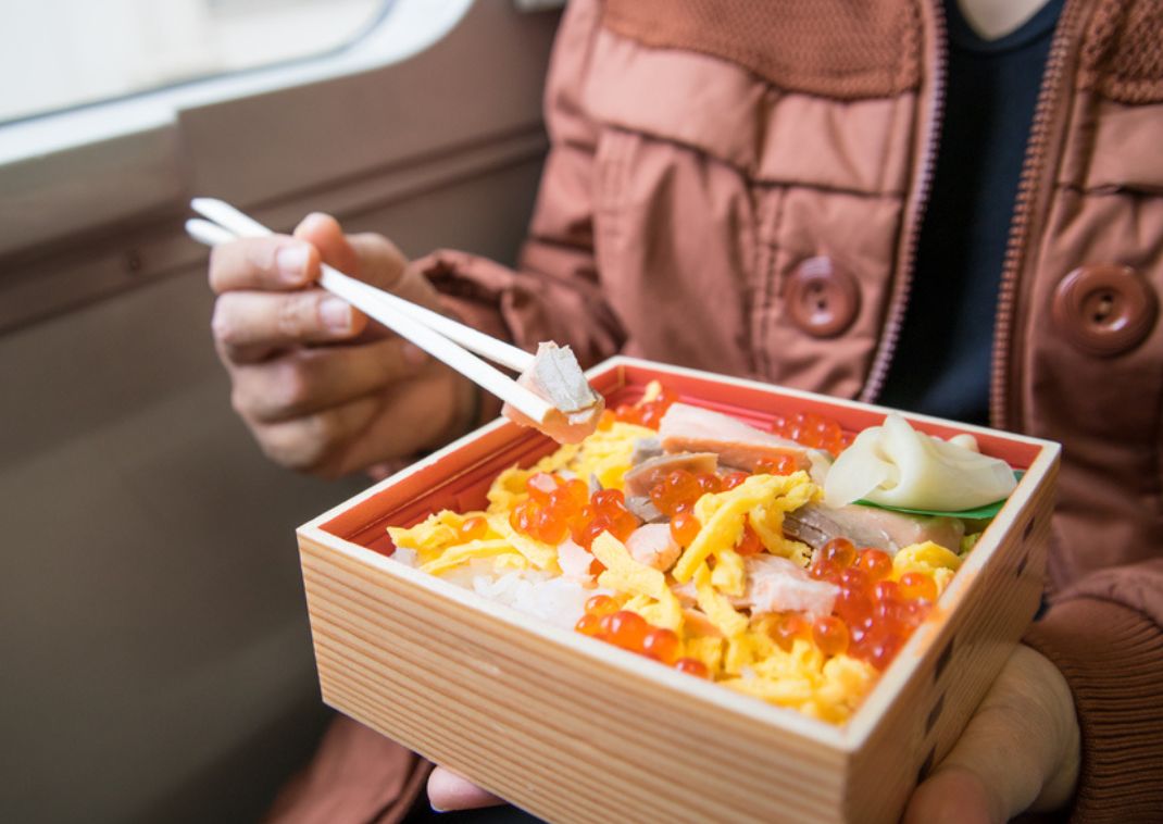 Turista che mangia un bento sullo shinkansen, Giappone