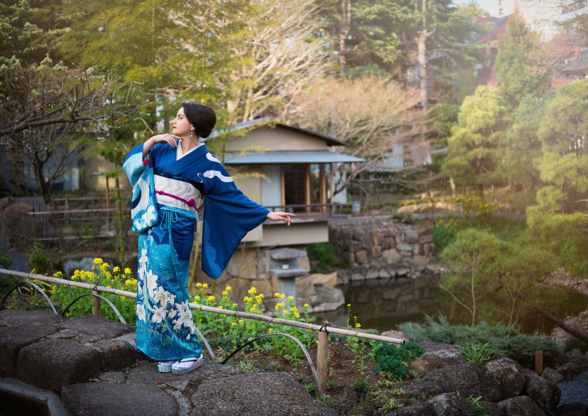 Donna con un kimono homongi blu in un giardino giapponese