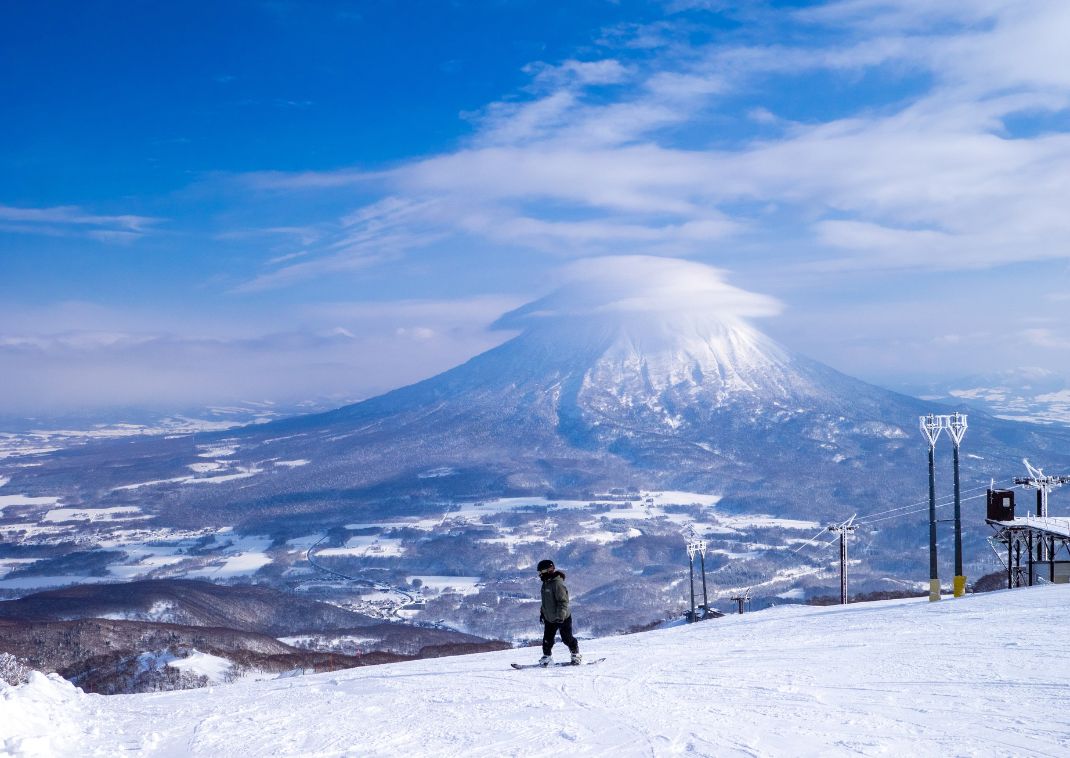 Vulcano innevato con nube a cappello visto da una stazione sciistica