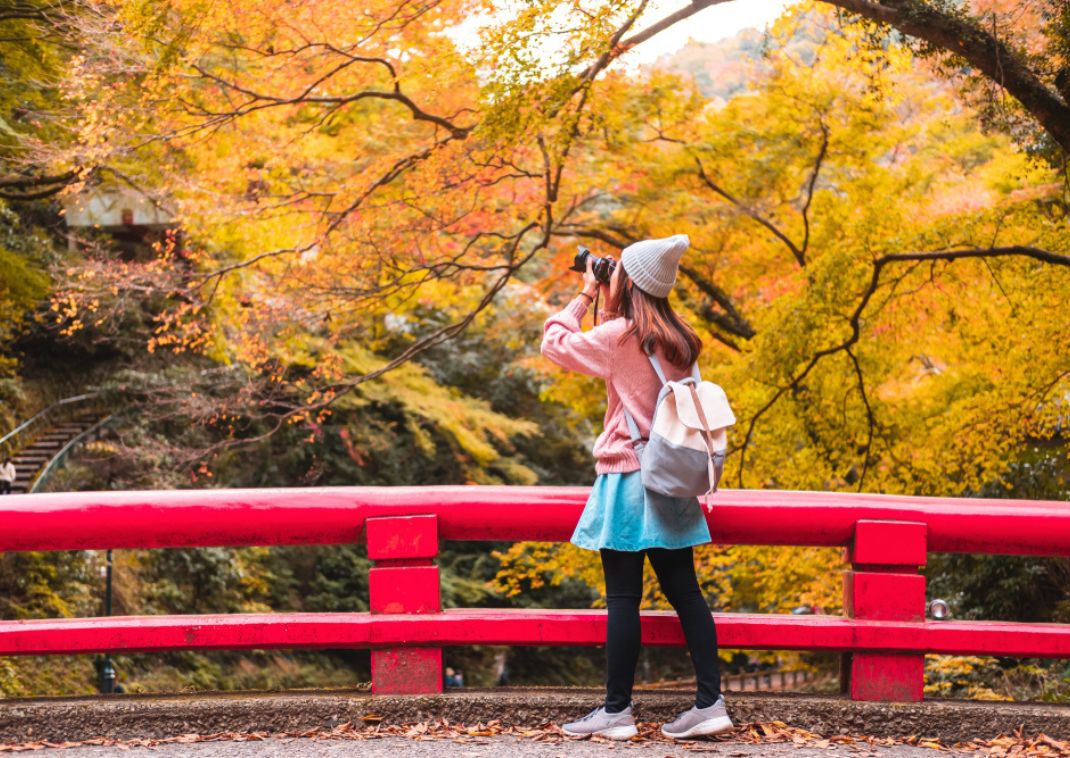 Una giovane viaggiatrice che fotografa il meraviglioso autunno in Giappone