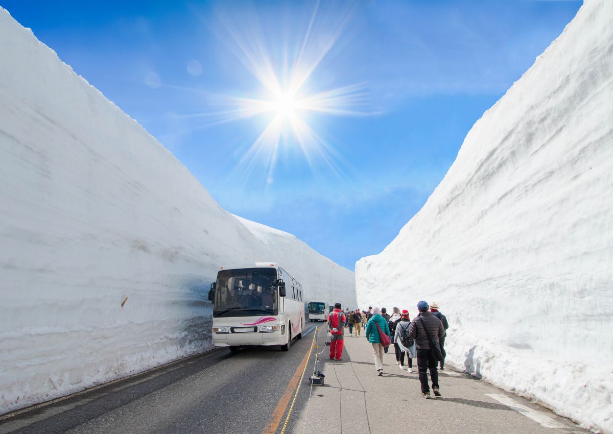 Le alte pareti di neve del percorso alpino Tateyama Kurobe sotto il cielo azzurro