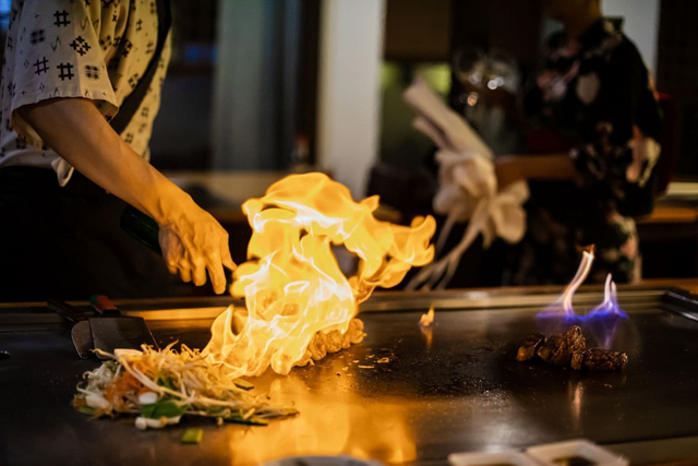 Lo chef prepara un piatto teppanyaki con carne di manzo alla griglia e verdure