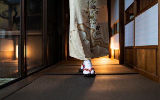 Donna in kimono che cammina in un ryokan tradizionale con stuoie tatami e porte shoji