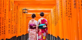 Due geishe tra le porte tori in legno rosso del santuario Fushimi Inari a Kyoto