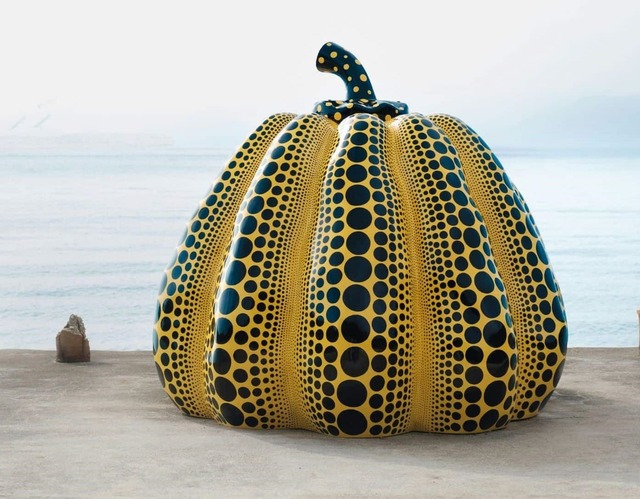 La scultura di Yayoi Kusama raffigurante una zucca gialla con puntini neri su uno sfondo blu vicino all'acqua a Naoshima