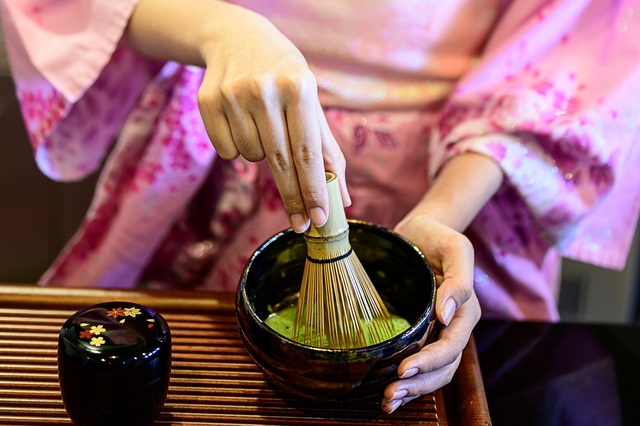 Signora in kimono che prepara il tè verde giapponese
