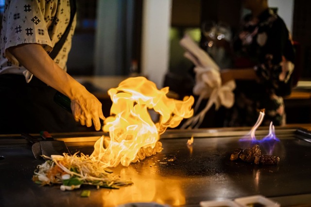 Lo chef prepara un piatto teppanyaki con carne di manzo alla griglia e verdure