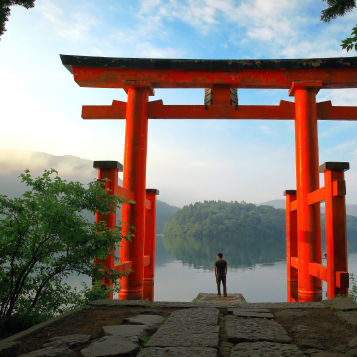 Turista davanti al cancello torii rosso del santuario di Hakone, situato sul lago Ashi, Giappone