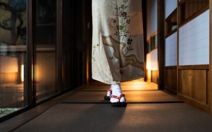 Donna in kimono che cammina in un ryokan tradizionale con stuoie tatami e porte shoji