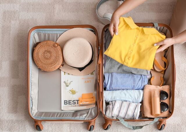 Donna che mette una maglietta gialla in una valigia estiva per un viaggio in Giappone.