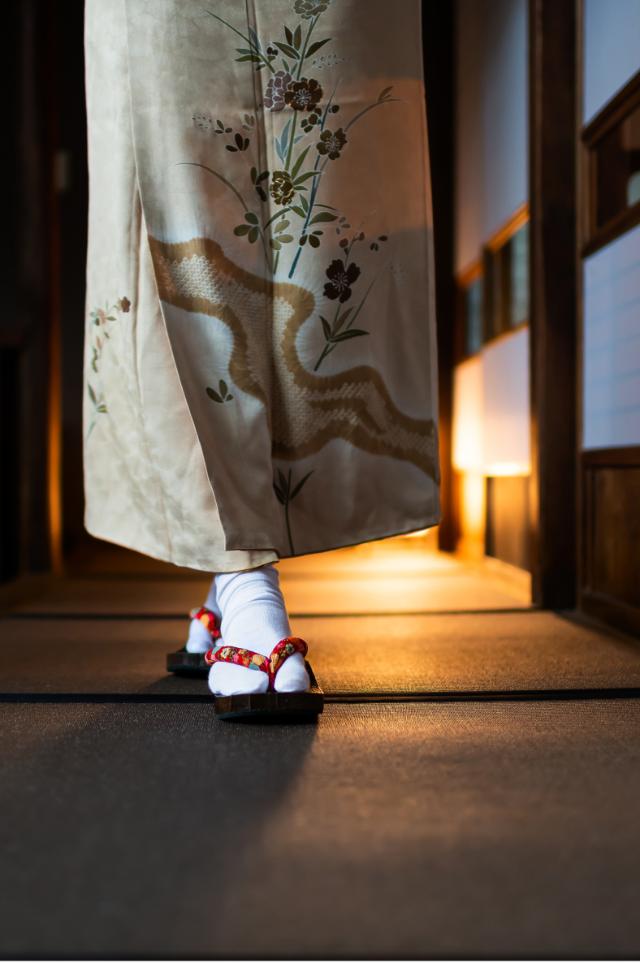 Donna in kimono che cammina in un ryokan tradizionale con stuoie tatami e porte shoji